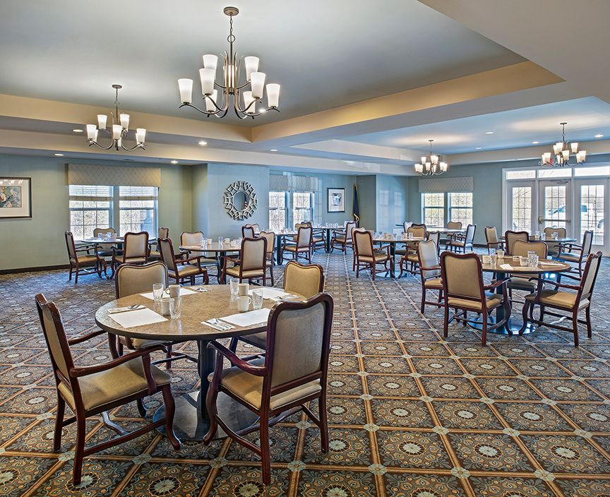 A spacious dining room with elegant chandeliers and neatly arranged tables ready for guests.
