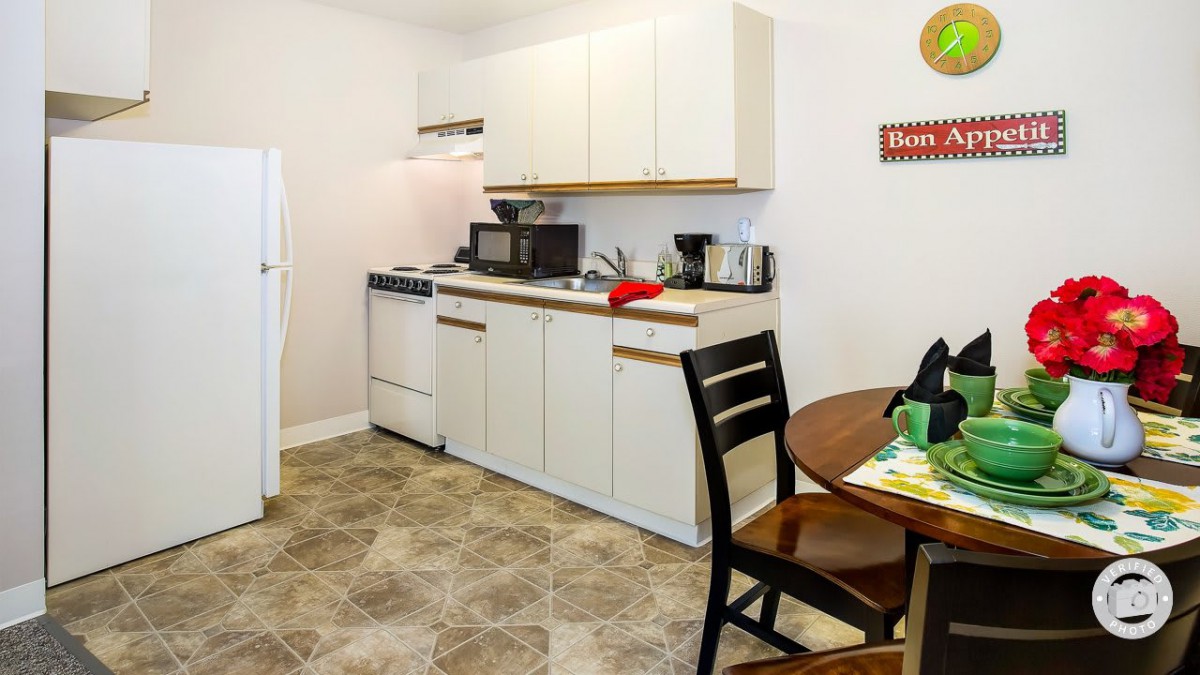 A compact kitchen space in an apartment with basic amenities including an oven, microwave, and a dining area.