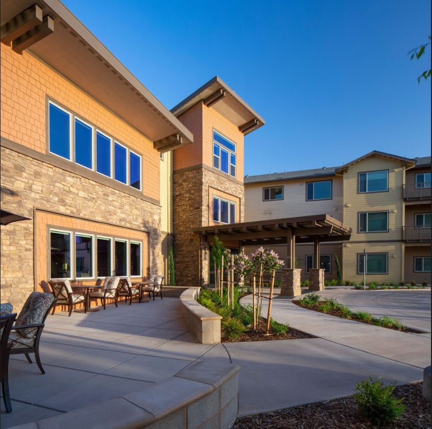 A modern residential building with a spacious courtyard and large windows under a clear blue sky.