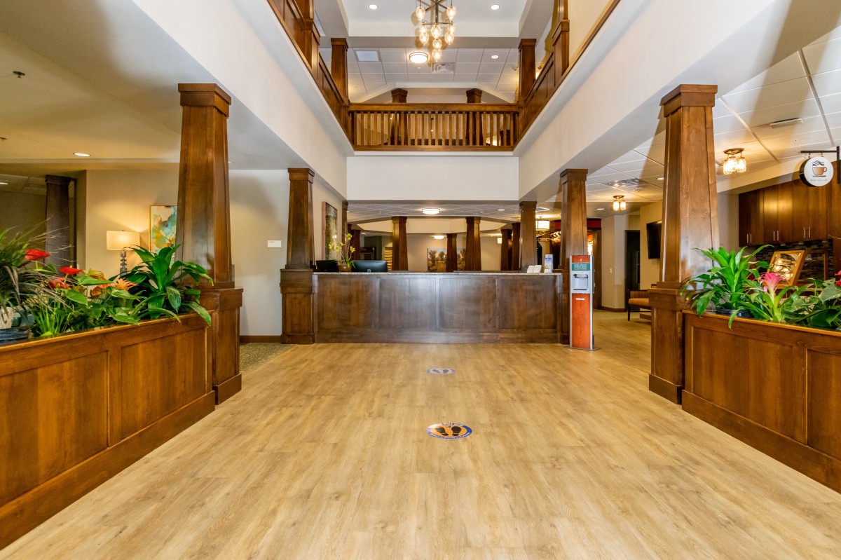 A spacious hotel lobby with wooden decor, featuring a reception desk and chandeliers.