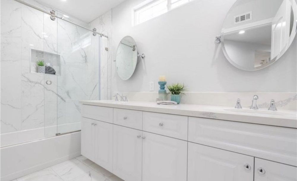 A modern, white bathroom with a shower and neatly organized counter space.