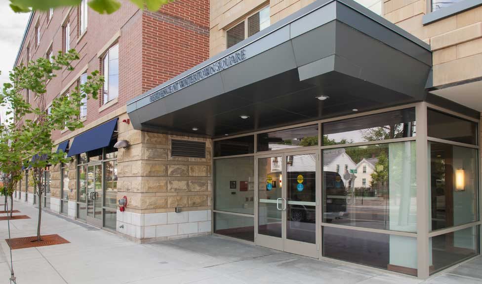 A modern building entrance with glass doors and a covered awning.