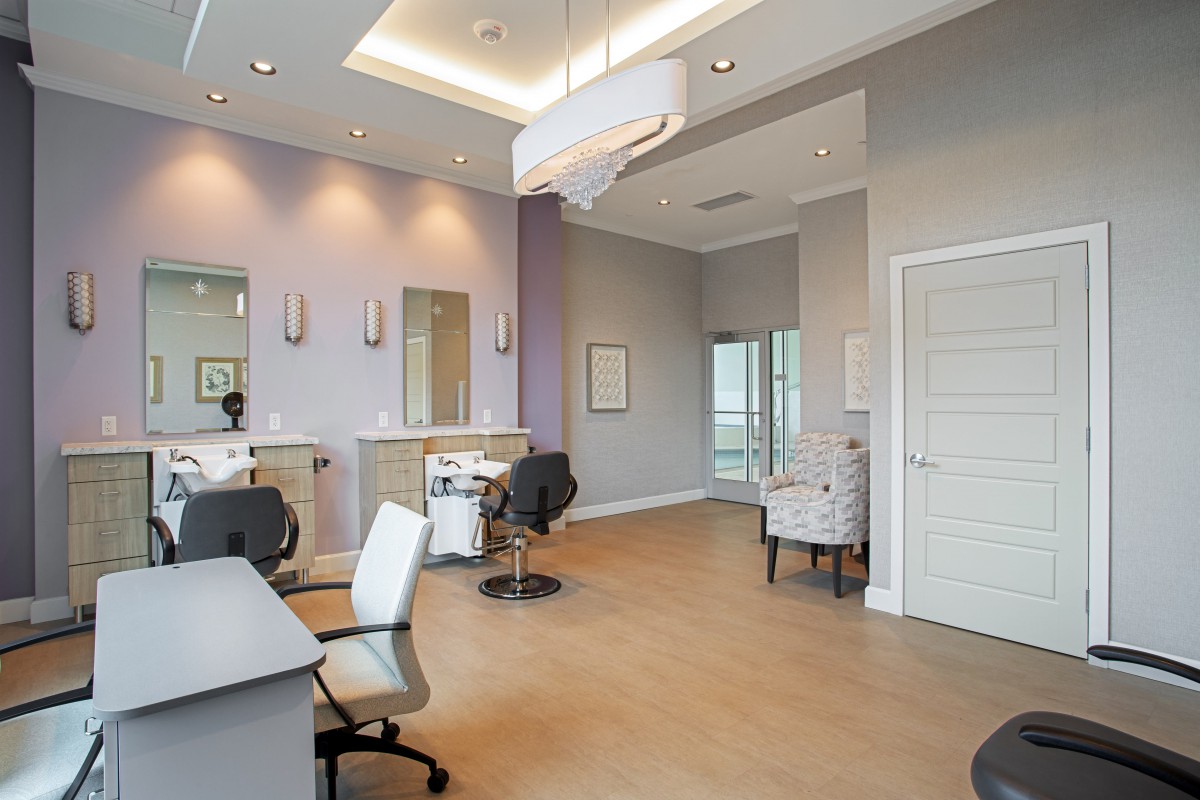 A modern salon interior featuring styling stations with chairs, mirrors, and bright overhead lighting.