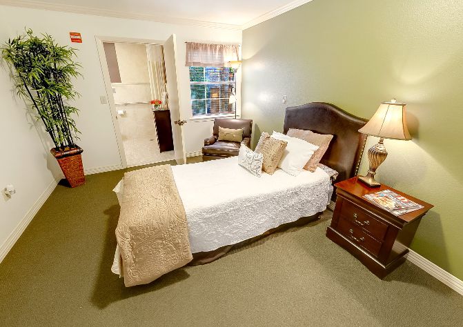 A cozy bedroom featuring a neatly made bed with cushy pillows, elegant nightstands, and warm lighting.