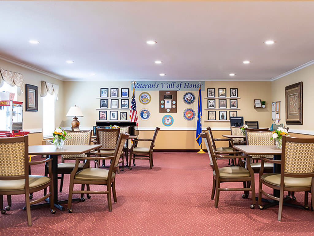 A well-organized dining area with neatly arranged tables and chairs, decorated with framed photos and flags on the walls.
