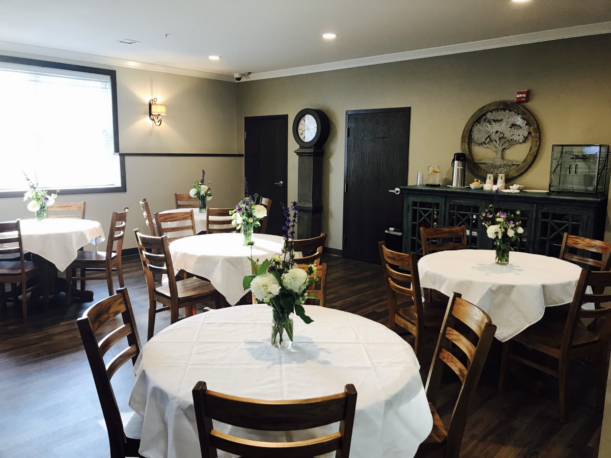 A cozy restaurant interior with round tables and floral centerpieces.