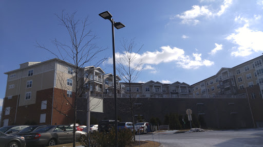 A sunny day in a residential parking lot with buildings and street lights.
