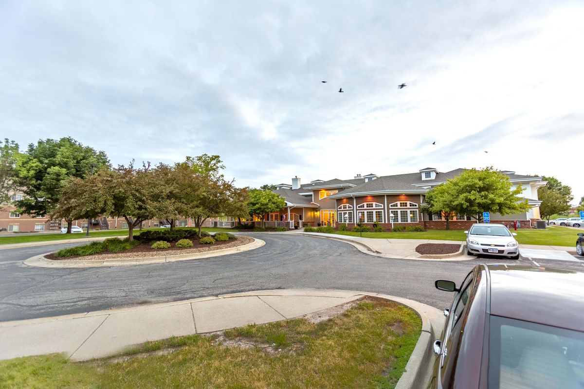 A view of a building with a parking lot and trees during the evening.