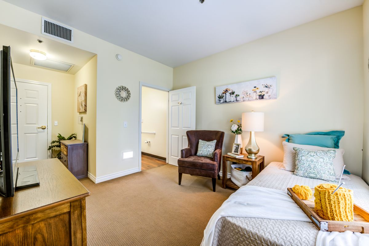 A cozy bedroom with a comfortable chair, bedside table, and soft lighting.