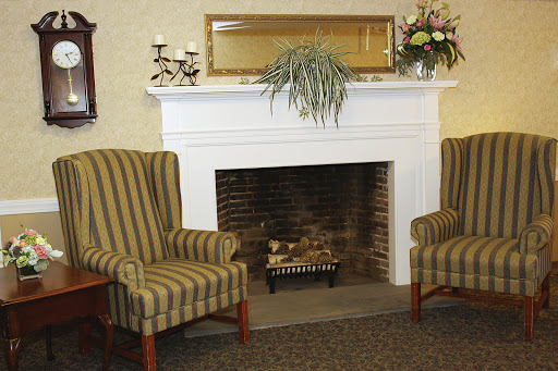 A cozy living room setting featuring a classic fireplace, comfortable striped chairs, and decorative elements.