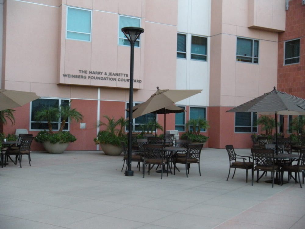 Outdoor seating area with tables and umbrellas near a building.