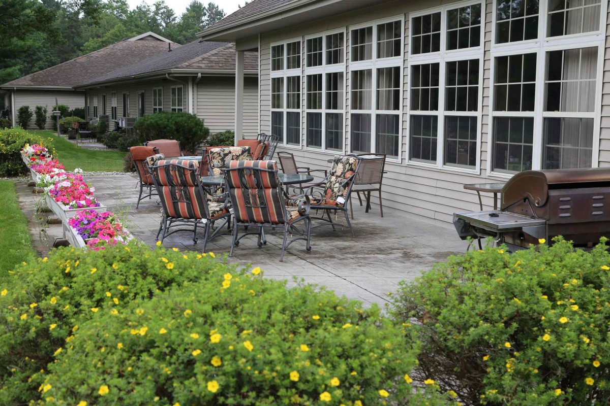 A cozy outdoor patio with a table and chairs surrounded by greenery.