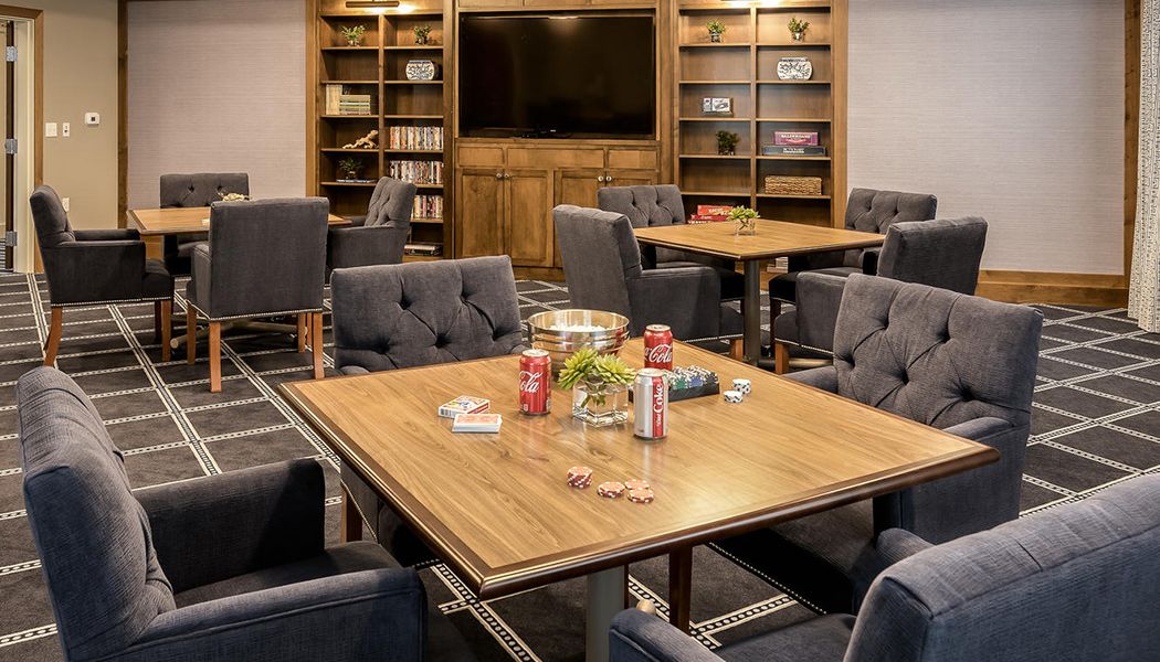 A cozy meeting room with bookshelves, comfortable seating, and a central table surrounded by chairs.