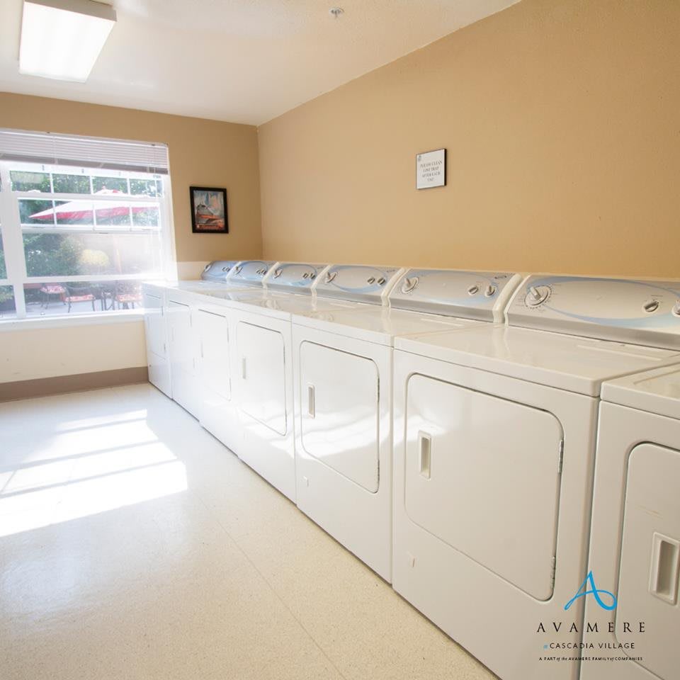 A bright and clean laundry room with multiple washers and dryers lined up against the wall.