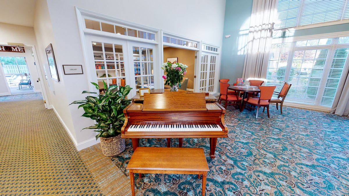 A cozy room with a wooden piano and bench, surrounded by plants and elegant decor.