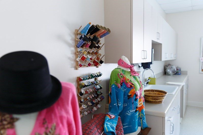 A vibrant sewing workspace with mannequins dressed in colorful fabric and organized thread racks.