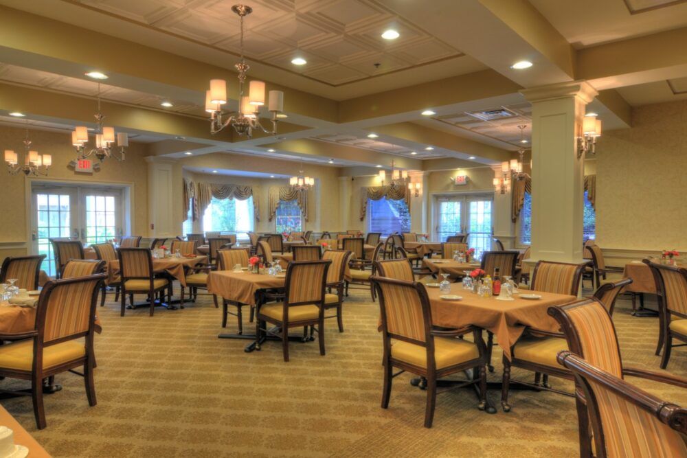 Elegant dining area with tables and chairs set under chandeliers.