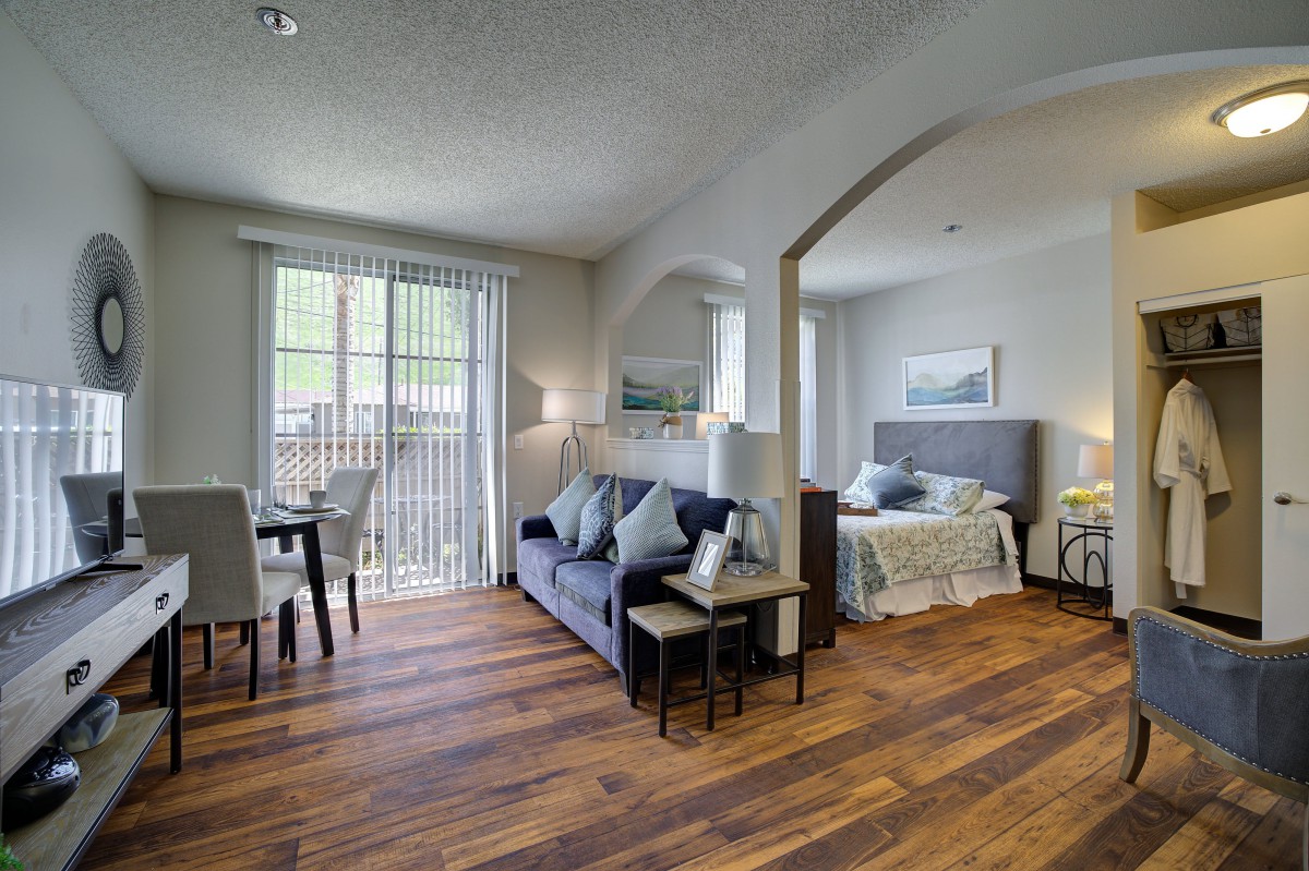 A spacious open floor plan with a modern living room and bedroom, featuring hardwood floors and elegant decor.