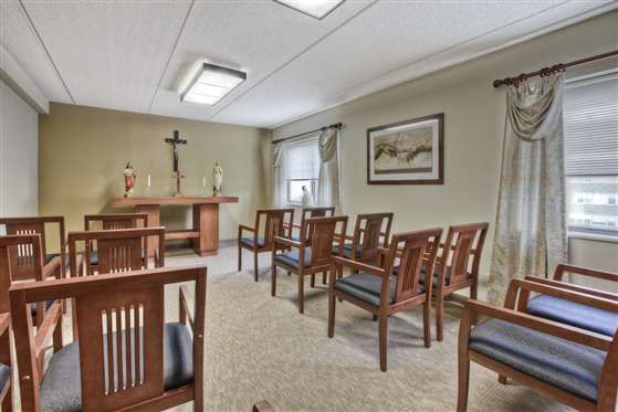 A serene chapel with simple wooden seating and religious symbols.