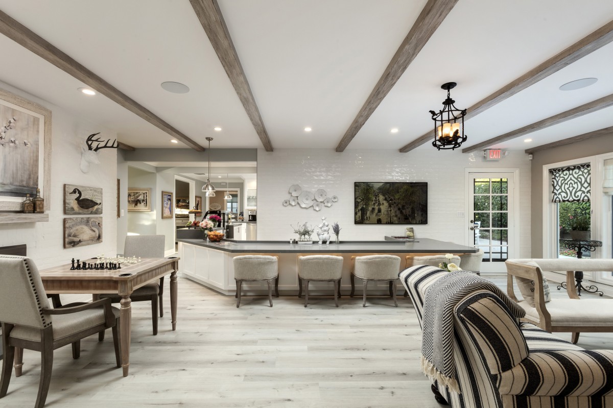 A modern open-concept kitchen with a large island, sleek counter stools, and elegant pendant lighting.