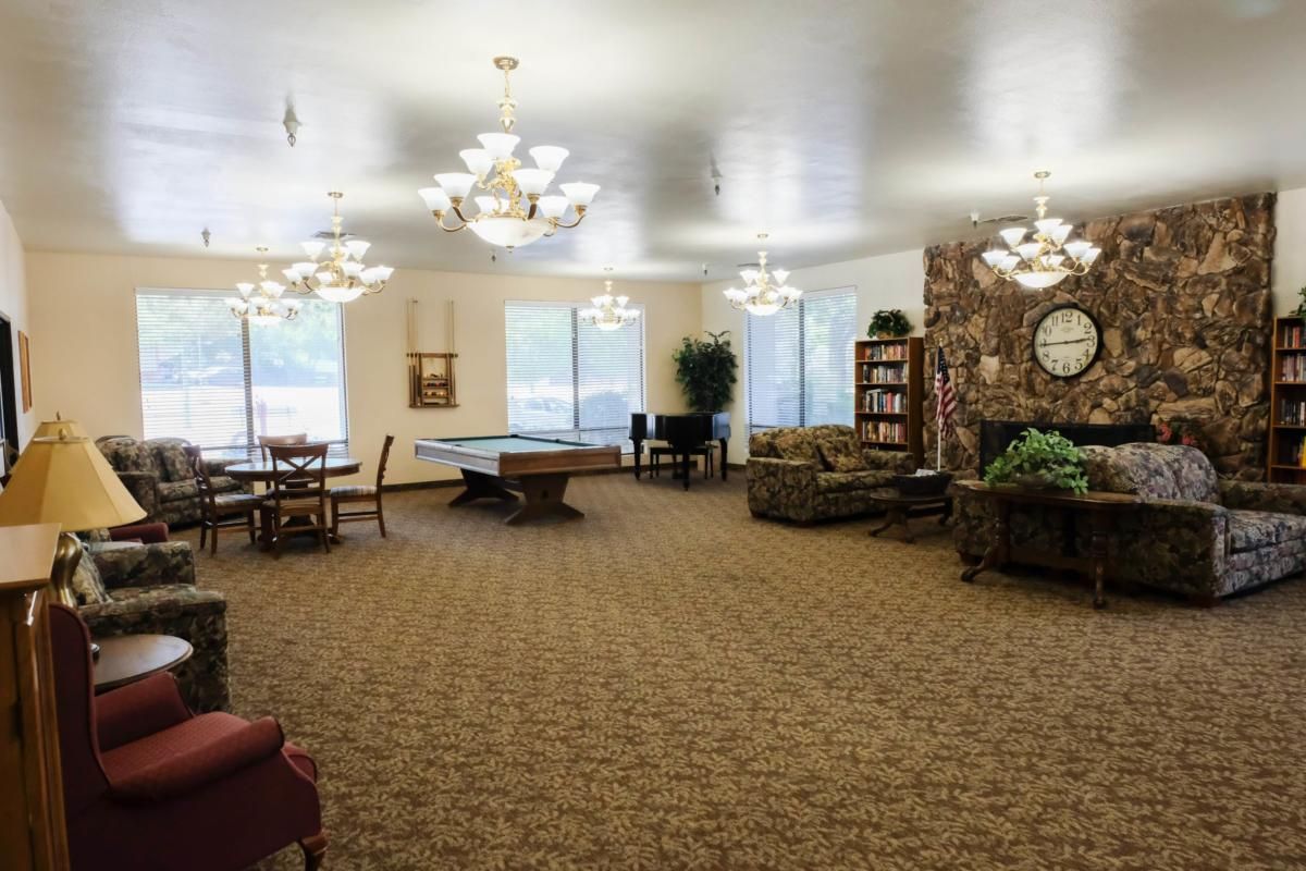 A spacious recreation room featuring a pool table, comfortable seating, and elegant chandeliers.
