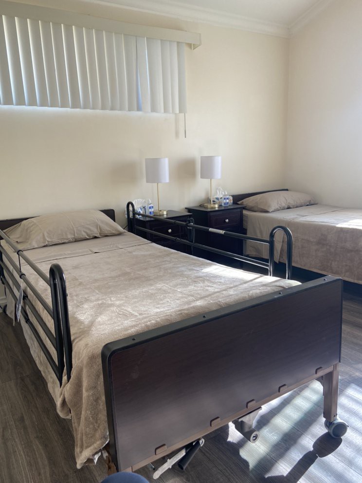 A room with two single beds, one of which is a hospital-style bed, in a healthcare or nursing facility.