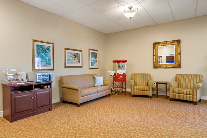 A cozy living room with a couch, two chairs, and a popcorn machine.