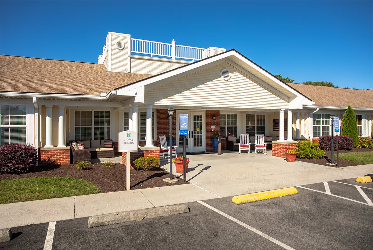 The front entrance of a residential care facility with a small parking area in front.