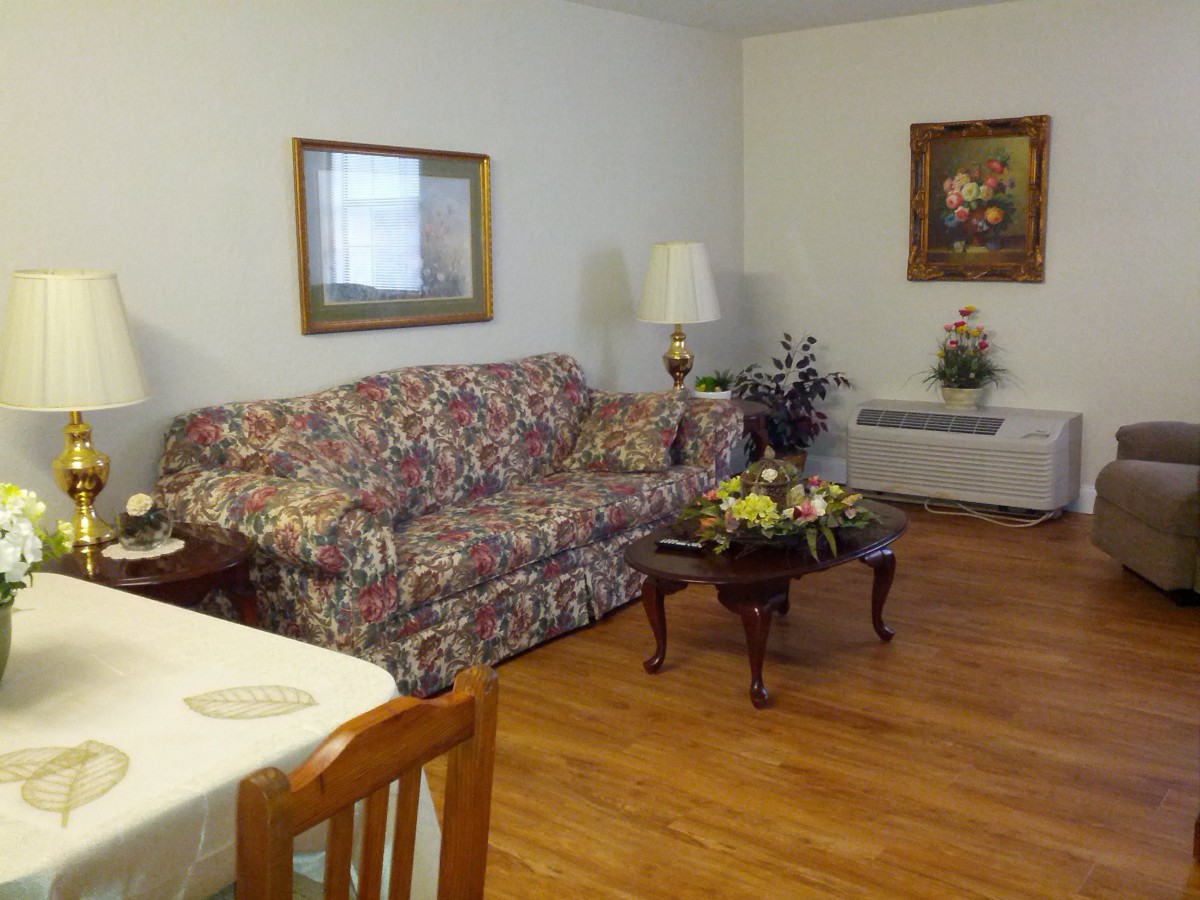 A cozy living room with a floral sofa, coffee table, lamps, and artwork on the walls.
