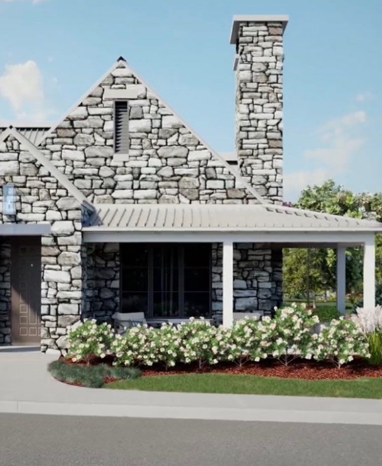 A charming house with a stone facade and chimney, complemented by a cozy porch and vibrant landscaping.