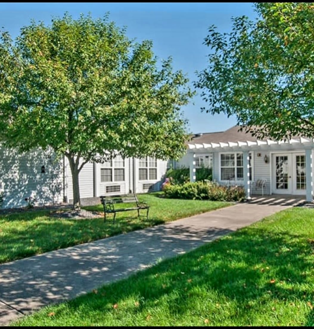 A picturesque residential house with a well-maintained lawn and trees on a sunny day.