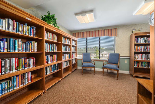 A cozy reading nook in a library with wooden bookshelves and comfortable chairs by the window.