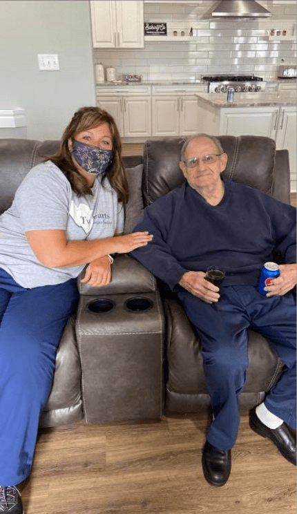Two people sitting on a couch, one wearing a mask.