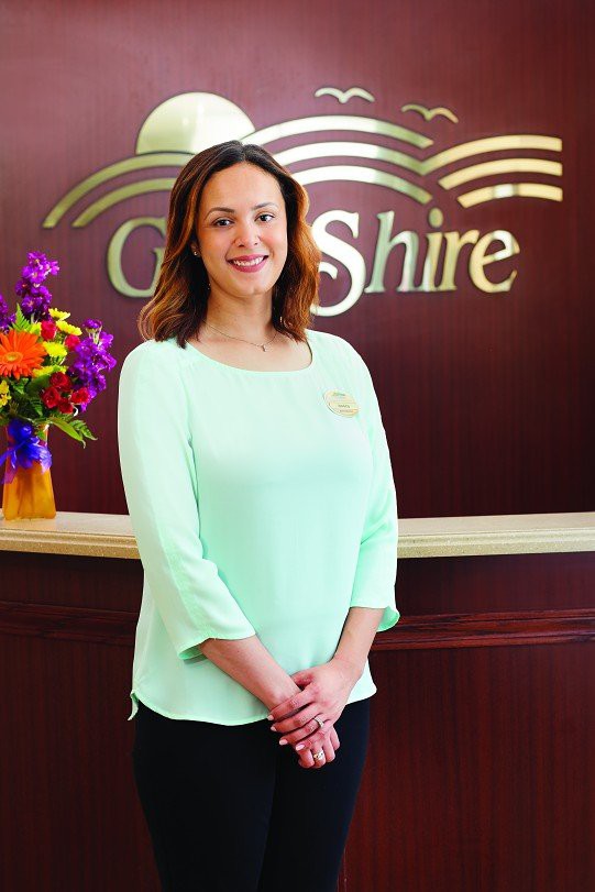 A woman stands in a professional reception area, smiling for the camera.