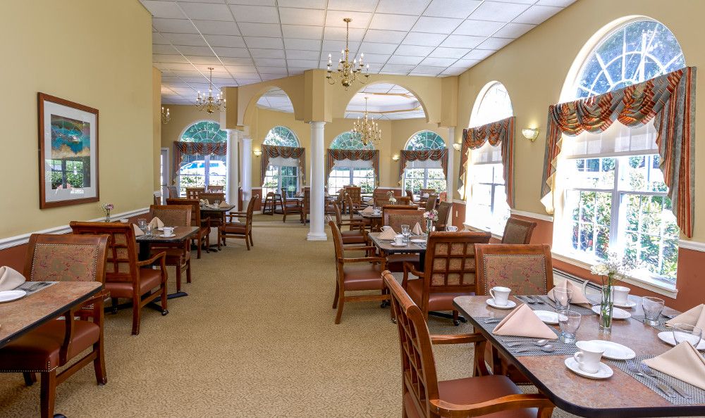 A well-lit dining area with elegant wooden furniture and large windows.