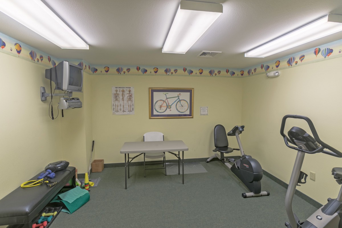 A small gym room with exercise equipment including a stationary bike and a weight bench.