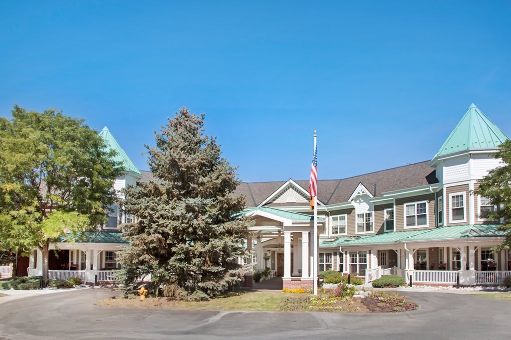 A residential building with a front entrance, surrounded by trees, under a clear blue sky.