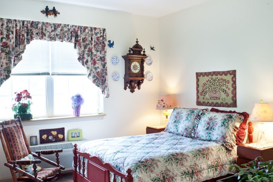 A vintage-style bedroom featuring floral patterns, a wooden bed frame, and an ornate wall clock.
