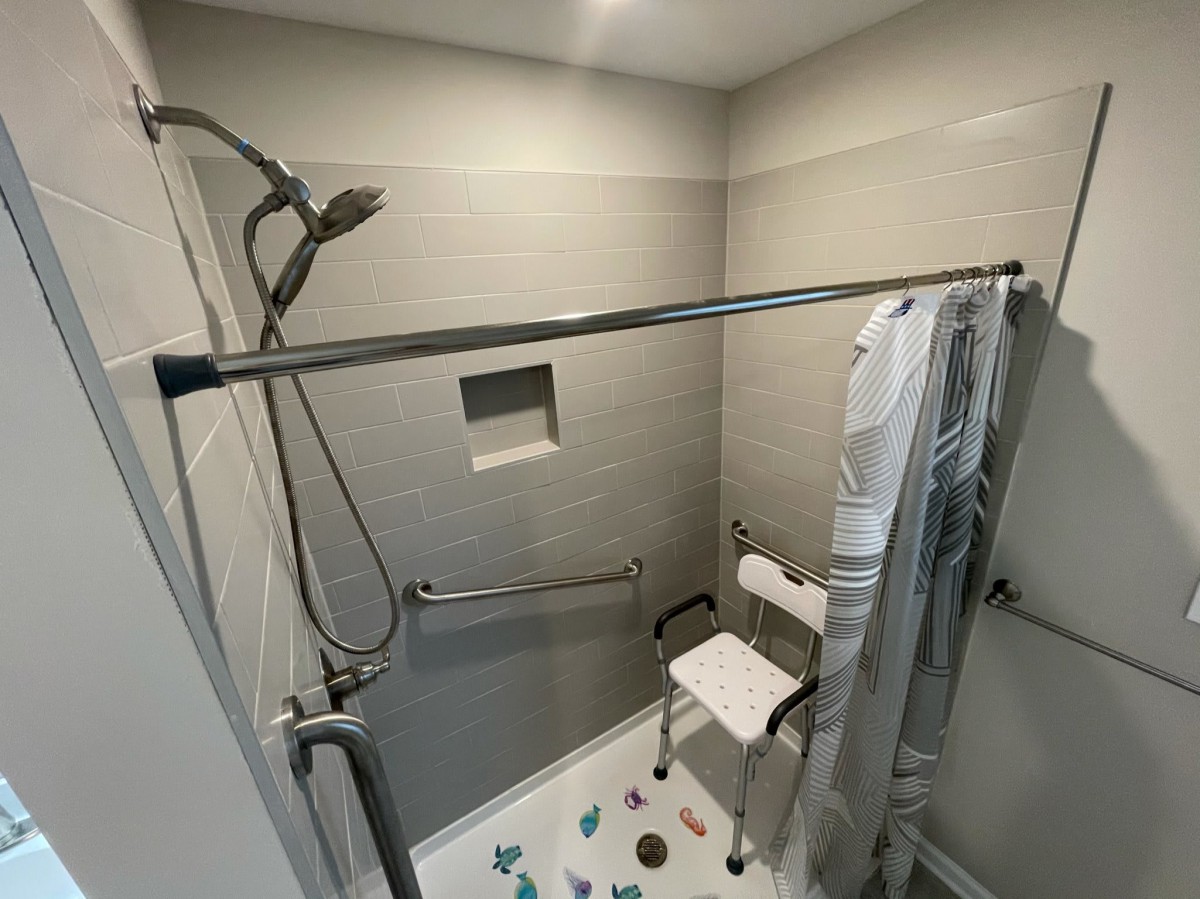 Accessible shower with grab bars and a shower chair.