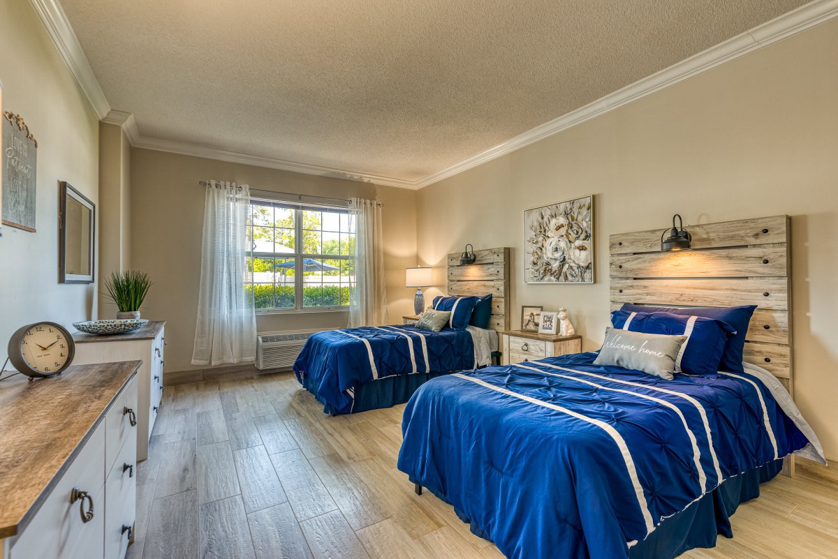 A cozy bedroom featuring twin beds with blue bedding and modern decor.