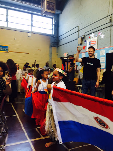 Children dressed in traditional attire proudly showcase the Paraguayan flag during a cultural celebration.