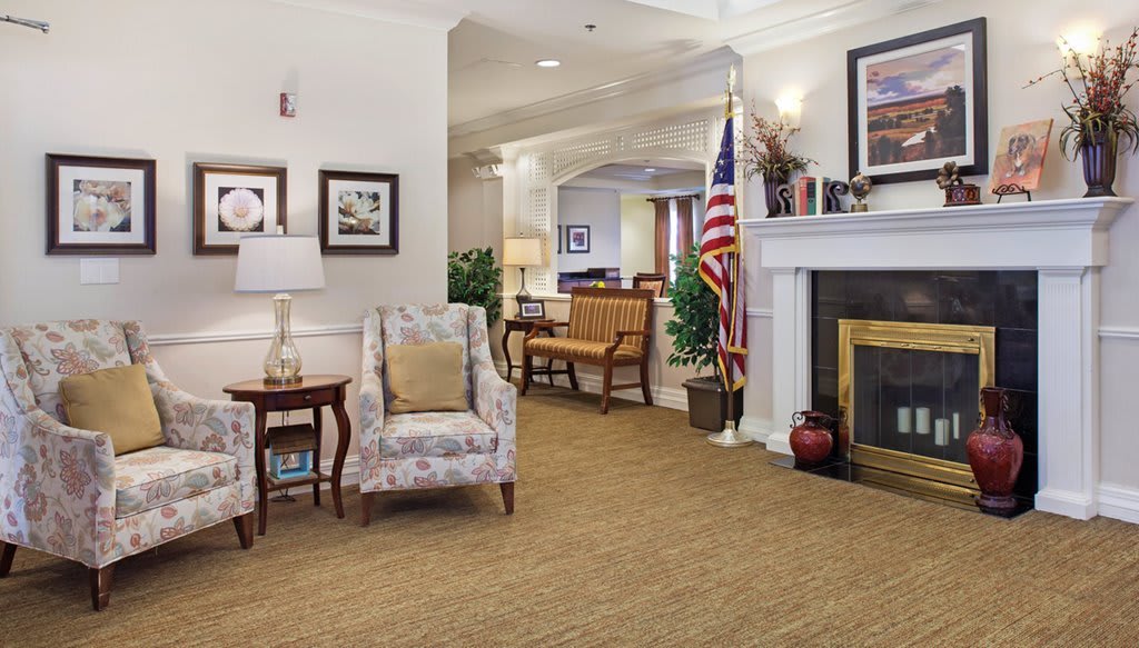 A cozy living room featuring a fireplace, armchair, and an American flag.