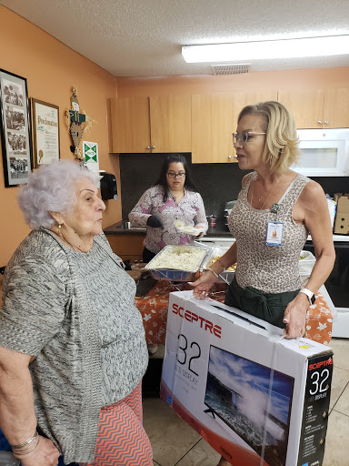 A joyful moment as a woman presents a 32-inch TV to an elderly lady during a gathering.