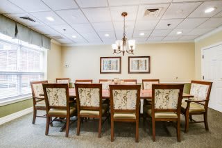 A spacious dining or meeting room with a long table and upholstered chairs.