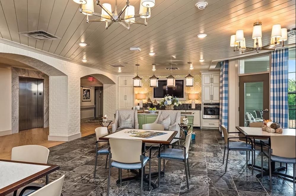A modern and cozy dining area with a view into the kitchen, featuring stylish chandeliers and comfortable seating.