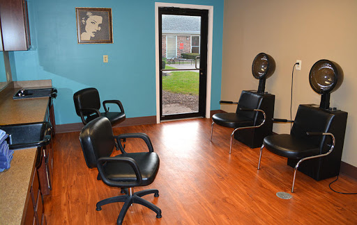 A cozy hair salon interior featuring a waiting area with black chairs and a hair dryer.