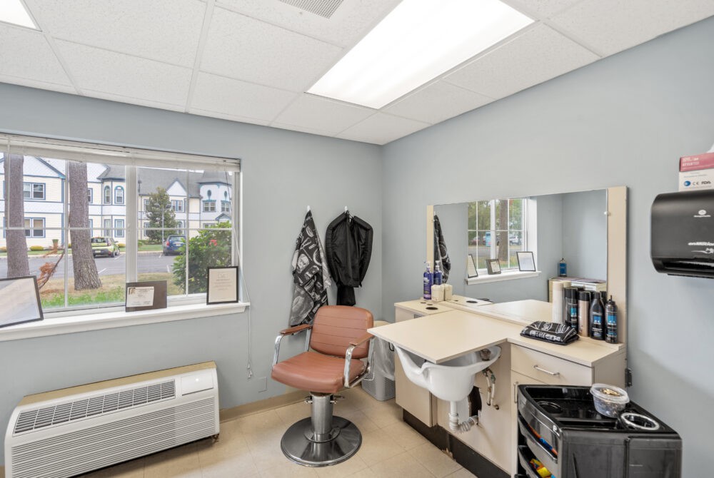 A well-lit hair salon interior with a styling chair, mirror, and sink.