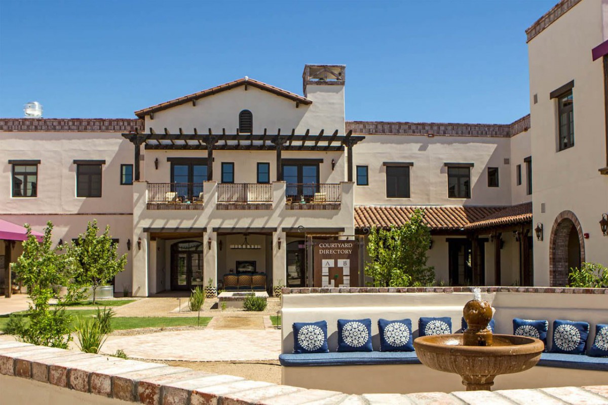 A luxurious Spanish-style mansion with a spacious courtyard and outdoor seating area.