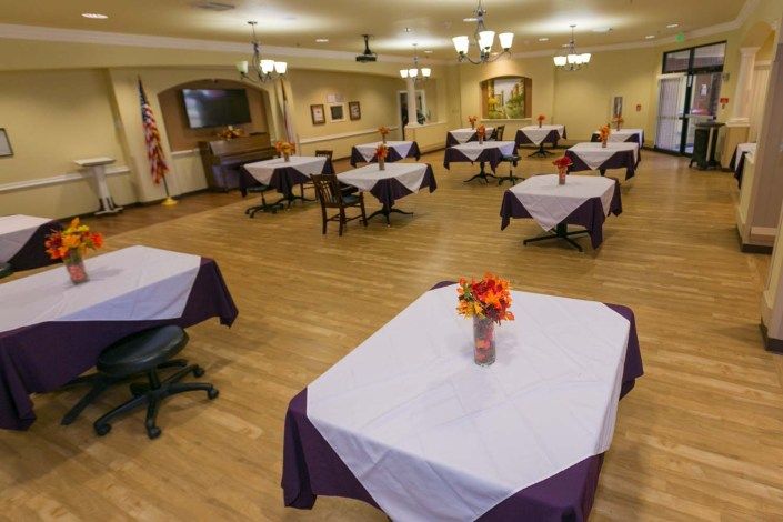 A decorated dining area with tables set with white tablecloths and flower centerpieces.