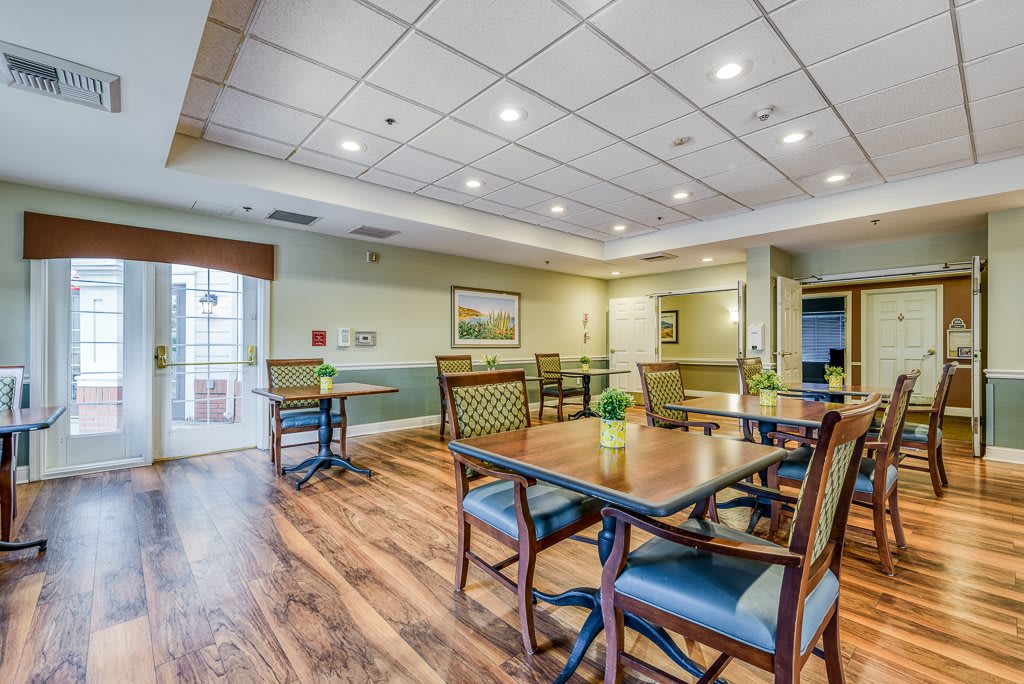 A well-lit dining area featuring wooden floors, tables, and chairs, creating a welcoming atmosphere.